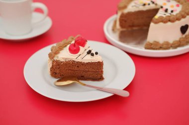 Beyaz bir tabakta servis edilen bir dilim çikolatalı pasta ve yanında altın bir kaşık.