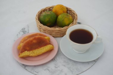 İki parça kue kusmuğu var. Geleneksel Endonezya sünger keki. Yumuşak pembe bir tabağa konmuş.