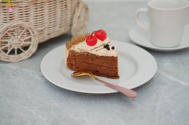 Beyaz tabakta kiraz soslu lezzetli bir dilim çikolatalı pasta..