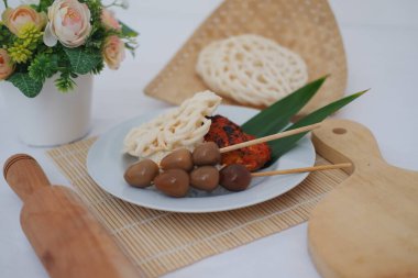 Beyaz bir tabakta Endonezya sokak yiyecekleri Sate, Yumurtalar ve Krakerler