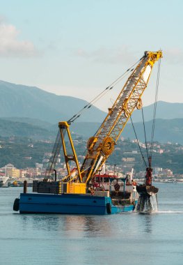 Limanda çalışan kapan kovayla uçan vinç süzgeci.