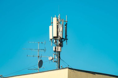 Çatıdaki cep telefonu ve televizyon antenleri açık mavi gökyüzüne karşı