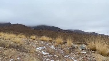 View from the height of the beautiful high-altitude lake Issyk-Kul in cloudy weather. The pearl of Kyrgyzstan is Lake Issyk-Kul. A calm, peaceful natural background. Mountain panoramic landscape.