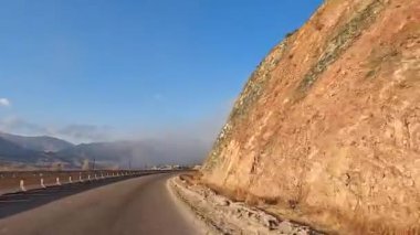 Traveling by car on a mountain road. Road adventure in the mountains of Kyrgyzstan. Amazing view of the beautiful mountain landscape. A snow storm is approaching in the distance.
