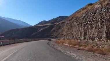 Amazing view of the beautiful hilly landscape. Serpentine roads. An exciting road adventure in the mountains of Kyrgyzstan. Traveling by car on a mountain road.