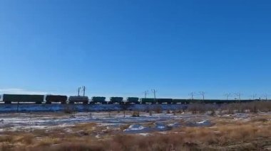 The train is traveling in the mountains of Kyrgyzstan. A sunny day. View of a long moving train with freight cars. An exciting road adventure.