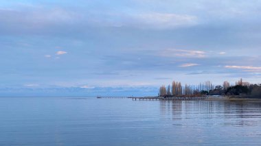 Beautiful view of the amazing mountain lake at sunset. The pearl of Kyrgyzstan is Lake Issyk-Kul. Calm calming natural background. Summer landscape.
