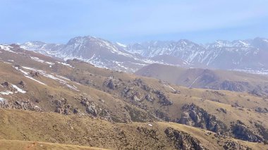 Tepelerin ve karla kaplı dağların güzel manzarası. Dağ manzarası. Doğal sakin bir geçmişi var. Kırgızistan 'ın inanılmaz doğası.