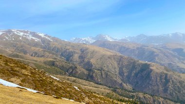 Uzaktaki sarı tepeler ve karlı dağlar. Dağ manzarası çok güzel. Mavi gökyüzü. Doğal sakin bir geçmişi var. Kırgızistan 'ın inanılmaz doğası.
