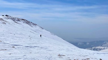 Yalnız turist bir tepenin yamacında duruyor. Düşük ihtimal. Güzel kış dağ manzarası. Kırgızistan 'ın inanılmaz doğası. Doğal sakin arkaplan.