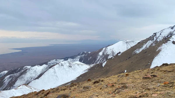 イシク クル湖の空中風景 雪の美しい景色帽をかぶった山々 山の風景 曇った空 岩や疎な植生 キルギスの素晴らしい自然 自然の穏やかな背景 — ストック写真
