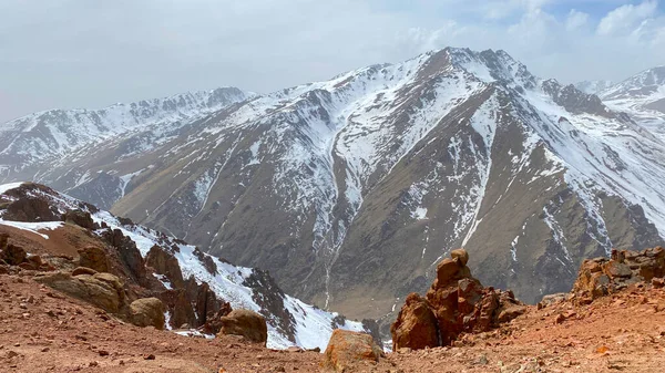 Stock image The amazing nature of Kyrgyzstan. Amazing mountain landscape. Panorama of red rocky cliffs and snow-capped mountains. Blue sky and white clouds. Natural calm background.