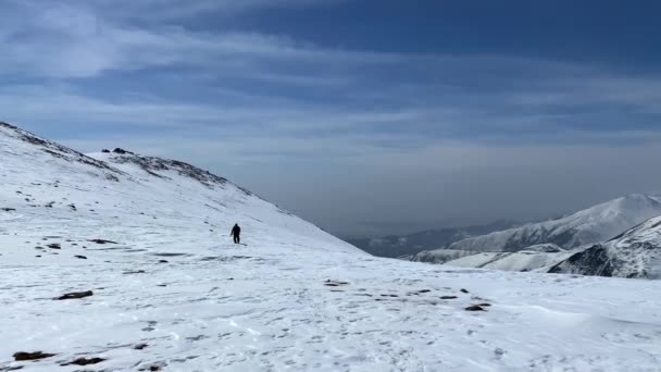 ローンの観光客は雪を歩く帽をかぶった山々 長いショット 美しい冬の山の風景 キルギスの素晴らしい自然 — ストック動画