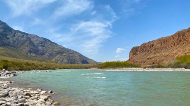 Güzel bir dağ gölü manzarası. Kaya kıyısı. İnanılmaz bir dağ manzarası. Kırgızistan 'ın doğası. Mavi gökyüzü ve beyaz bulutlar.