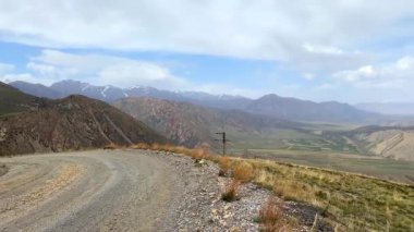 Kırgızistan 'da güzel bir dağ vadisi manzarası. İnanılmaz bir dağ manzarası. Mavi gökyüzünün yüksekliğinden, beyaz bulutlardan, yeşil tarlalardan, sırtlardan ve tepelerden bak..