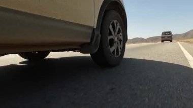 Sağ ön tekerlekten arka tekere geçiş. Hareket halindeki bir off-road aracının sağ arka tekerleğinin görüntüsü. Yakın plan. Kırgızistan 'da arabayla seyahat ediyor. Heyecan verici bir yolculuk..