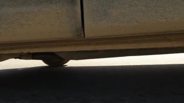 Arabanın sağ arka tekerinden ön tekere geçiş. Bir SUV aracının sağ ön tekerleği, yol ve önünde hareket eden bir minivan görünüyor. Yakın plan. Kırgızistan 'da arabayla seyahat ediyor. Heyecan verici bir yolculuk..