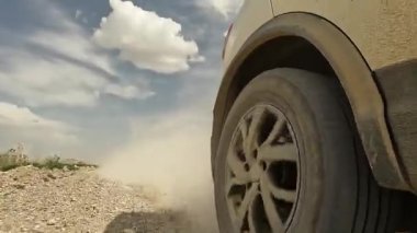 Kırgızistan 'da arabayla seyahat ediyor. Toprak kayalık bir yolda giden bir arabanın yakın çekimi, toz yaratıyor. Hareket halindeki bir cipin sağ arka tekerleğinin görüntüsü. Heyecanlı bir yol macerası.