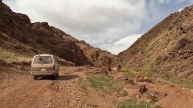 Minibüs pitoresk bir geçitten geçiyor. Güzel dağ vadisi. Toprak yol, kayalar, mavi gökyüzü ve beyaz bulutlar. İnanılmaz bir manzara. Kırgızistan 'da heyecanlı bir yol macerası.