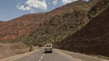 Resimli dağ vadisi. Yeşil çalıları olan çok renkli güzel dağlar. Kırgızistan 'da minivanla seyahat ediyor. Çöl manzarası. Heyecanlı bir yol macerası.