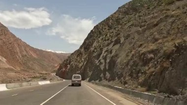 Kırgızistan 'da heyecanlı bir yol macerası. Resimli bir vadide minivanla seyahat etmek. Güzel dağ vadisi. Renkli kayalar, yeşil tepeler ve karlı dağlar. İnanılmaz manzara..