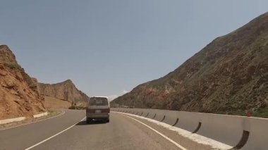 İnanılmaz bir dağ manzarası. Güzel dağ vadisi. Minibüs pitoresk bir geçitten geçiyor. Renkli kayalar, yeşil tepeler ve ağaçlar. Kırgızistan 'da heyecanlı bir yol macerası.