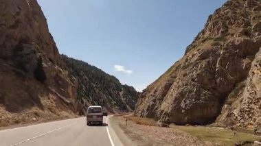 Minivan güzel bir dağ geçidinden geçiyor. Dağ vadisi manzarası. Kırgızistan 'da heyecanlı bir yol macerası. İnanılmaz dağ manzarası..