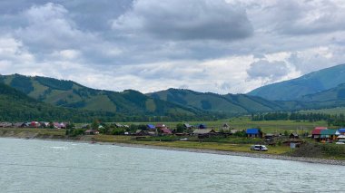 Katun Nehri kıyısındaki Rus köyü, Altai, Rusya. Yeşil ağaçlık tepeler, tepeler ve dağlar. Katun Nehri 'nin yüksekliğinden bak. Güzel yeşil vadi. Sakin doğal arka plan.