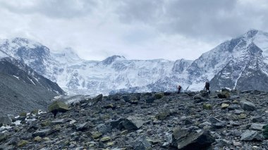 Büyük sırt çantalı iki dağcı kayalıklarda yürüyor. Belukha Dağı 'na tırmanıyorum. Güzel dağ kış manzarası. İnanılmaz doğal bir geçmişi var. Altai Dağları. Akkema duvarının görüntüsü.