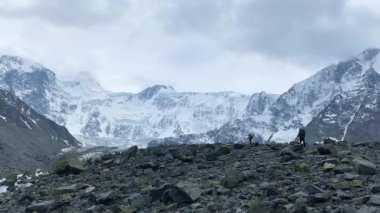 Büyük sırt çantalı iki dağcı kayalıklarda yürüyor. Belukha 'ya tırmanmak. Akkem Duvarı 'nın muhteşem manzarası, Altai, Rusya. Karla kaplı tepeler, tepeler, yamaçlar ve dağlar. Sakin doğal arka plan.