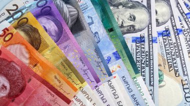 Kırgız banknotları farklı banknotlar ve birkaç banknot 100 Amerikan doları. Para değişimi kavramı. Kırgızistan ve Amerika 'nın nakit banknotları. Kırgız ve Amerikan ulusal para biriminin geçmişi.