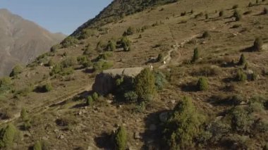 Kırgızistan 'daki Ala-Archa Ulusal Parkı' ndaki Kırık Kalp Turist otoparkı. İki turist büyük bir taşın üzerinde oturuyor. Dikiz aynası. Güzel dağ manzarası. Yeşil ağaçlar, çalılar ve kayalar. Dağlarda aktif eğlence..