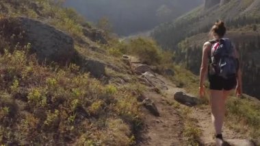 Küçük sırt çantaları ve yürüyüş direkleriyle bir grup turist dağ yolunda yürüyor. Kırgızistan 'daki Ala-Archa Ulusal Parkı. İnanılmaz bir dağ manzarası. Aktif boş zaman.