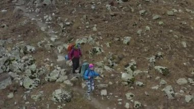 Sırt çantaları ve yürüyüş direkleriyle iki genç turist Kırgızistan dağlarında kayalık bir plato boyunca yürüyorlar. Ala-Archa Ulusal Parkı. Dağlarda aktif eğlence..