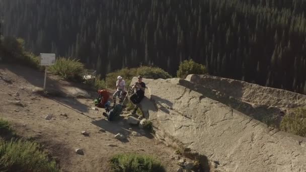 キルギスのアラ アルチャ国立公園 駐車場は壊れた心臓です 女の子と男の子が大きな石の上に座って休んでいる 山で夜明けする グリーンフォレスト 山のアクティブレクリエーション — ストック動画