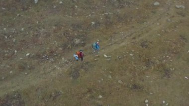 Büyük sırt çantaları ve yürüyüş direkleri olan iki aktif turist Ala-Archa Ulusal Parkı 'nın eteklerinde yürüyor. Yukarıdan bak. Dağlarda aktif eğlence..