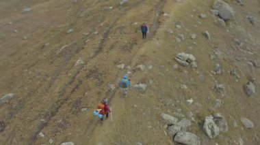 Büyük sırt çantaları ve yürüyüş direkleriyle iki turist küçük sırt çantalı iki kişiyle tanışıyor. Kırgızistan 'daki Ala-Archa Ulusal Parkı. Dağlarda aktif eğlence..