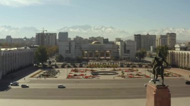 Bishkek şehir merkezinin muhteşem manzarası ve uzaktaki karlı dağ zirveleri. İhtişamlı Manas Anıtı. Bishkek Devlet Vergi Dairesi 'nin binası. Kırgızistan 'a seyahat.