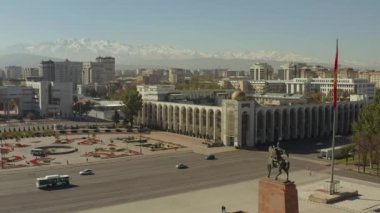 Bishkek 'in merkezindeki Manas anıtının yüksekliğinden uzaktaki karlı dağ zirvelerine kadar güzel bir manzara. Bishkek Devlet Vergi Dairesi 'nin binası. Kırgızistan 'a seyahat.