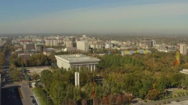 Kırgızistan 'ın başkentini dolaş. Bishkek 'in merkez caddesinin manzarası. Çeşitli binalar, anıtlar, parklar, ağaçlar, insanlar ve otoyollar.