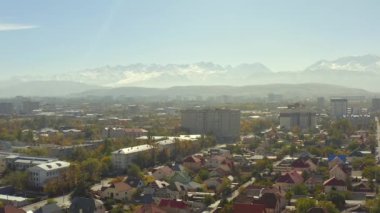 Sonbaharda güneşli bir gün Bishkek. Dağlar, tepeler, yamaçlar ve karlı tepeler. Özel sektör ve yüksek binalar. Kırgızistan 'a git. Yükseklerden manzara.