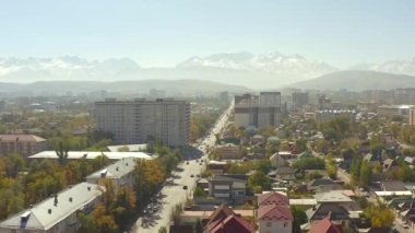 İnsansız uçak Bishkek üzerinde uçuyor. Özel evleri ve yüksek binaları olan bir yerleşim yeri. Sonbaharda güneşli bir gün Bishkek. Dağlar, tepeler, yamaçlar ve karlı tepeler. Kırgızistan 'a seyahat.