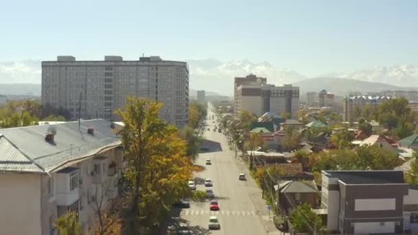 ビシュケクでの秋 高層ビルや民家を見ることができます キルギスの首都を飛行する 背景に雪に覆われた山々 車が道路を走っている キルギスへの旅行 — ストック動画