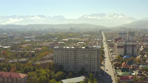 ビシュケクの緑地にある高層ビルの高さからの眺め キルギスの民家 遠くにある雄大な山々 キルギスの首都を飛行する無人機 ビシュケクでの秋 キルギスへの旅行 — ストック動画