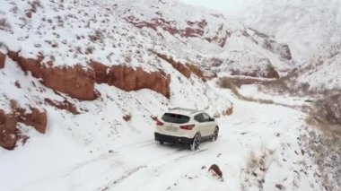 Konorchek Kanyonu. Kırgızistan 'da arabayla seyahat ediyor. Güzel dağ kış manzarası. SUV karlı bir dağ yolunda gidiyor..