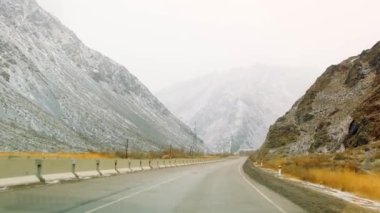 Kırgızistan 'da arabayla seyahat ediyor. Dağlarda elektrik hattı olan asfalt bir yol. Kırgızistan 'ın tepeleri, tepeleri, tepeleri, tepeleri, yamaçları. Güzel kış manzarası.