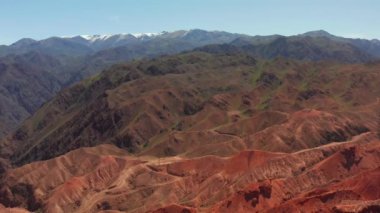 Kırgızistan 'daki Konorchek' in kızıl kayalık kanyonlarında İHA uçurmak. Kanyonlara ancak kurumuş bir nehrin yatağındaki kayalardan oluşan labirentlerden ulaşabilirsiniz. Resimli bir dağ yaz manzarası.