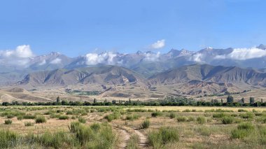 Issyk Kul Gölü yakınlarındaki Kırgızistan 'ın muhteşem dağlarına, tepelerine ve uçurumlarına bakan nefes kesici bir manzara. Kırsal toprak yol manzarası. Seyahat ve turizm. Gezinti ve yürüyüş. Güzel yaz manzarası 