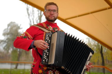 Elinde bir bayan ile Rus halk şarkılarının komik bir şarkıcısı. Kırmızı gömlekli ve gözlüklü bir adam parkta akordeon çalar. Müzisyen enstrüman çalmaktan hoşlandığı için görüntü sıcak ve davetkar bir ortam yaratıyor.