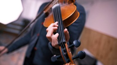 Kemancının elini kemanın tellerine yakın çekim, parmaklarına ve boynuna odaklan. Genç bir kadın keman çalıyor. Müzisyenin bir ilham acelesi var. Müzik okulu. Melodi